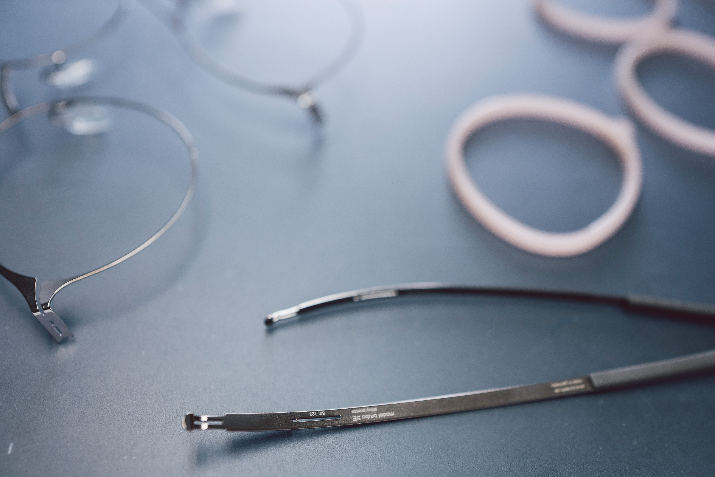 Close-up of ic! berlin stainless steel frame components and temples on the design table in the Berlin manufactory — precision engineering and screwless hinge construction