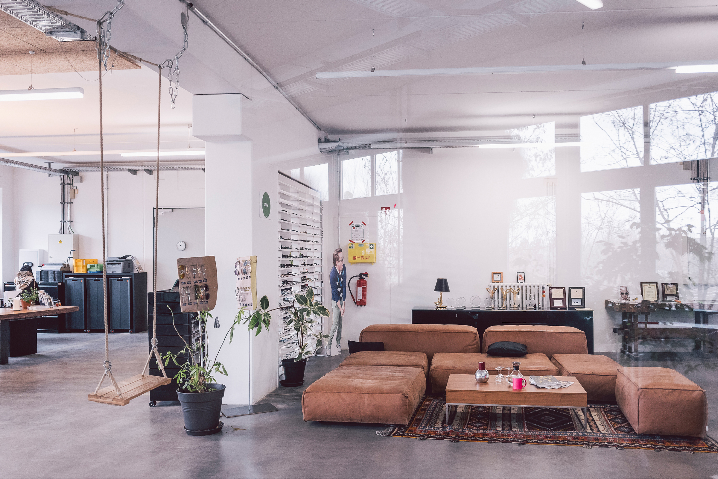 Interior of the ic! berlin Berlin manufactory and headquarters — industrial loft space with frames on display shelves, natural light, and design award trophies